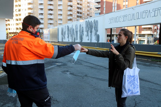 Protecció Civil repartint una mascareta a una noia