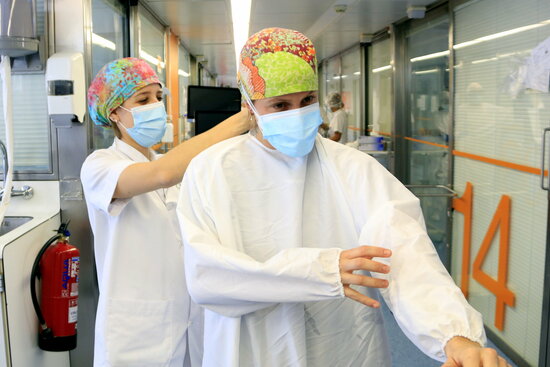 Una infermera de crítics es vesteix, ajudada per una companya, per entrar a l'UCI i atendre un pacient ingressat a causa de la covid-19. Foto: ACN.