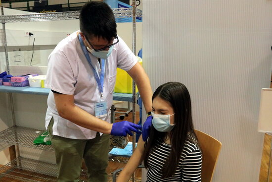 Un infermer administrant la vacuna contra la covid-19 a una jove. Foto: ACN.