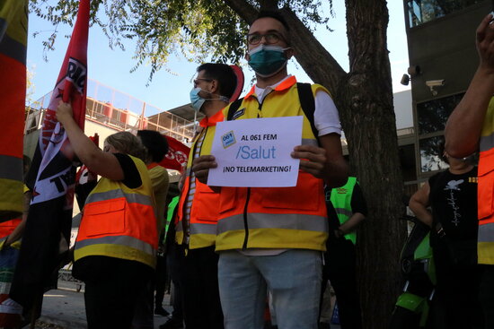 Un treballador donant suport a la vaga amb un cartell reivindicant que al servei del 061 no es fa "telemarketing". Foto: ACN.
