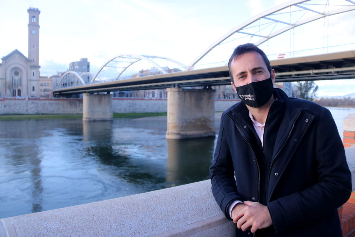 El candidat d'En Comú Podem a la circumscripció de Tarragona, Jordi Jordan, amb el pont de l'Estat de Tortosa i el riu Ebre al fons. Imatge del 27 de gener de 2021