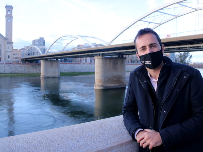 El candidat d'En Comú Podem a la circumscripció de Tarragona, Jordi Jordan, amb el pont de l'Estat de Tortosa i el riu Ebre al fons. Imatge del 27 de gener de 2021